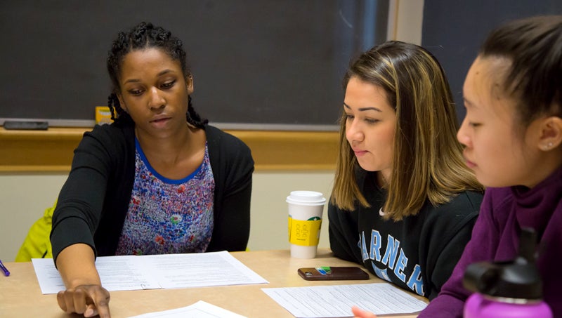 Three students discussing work on a paper.