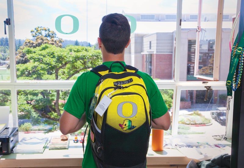 Student looking out window of residence hall.