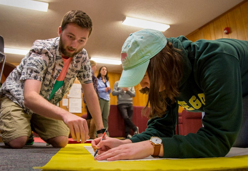 Photo of students using hamilton lounge writing on poster paper.