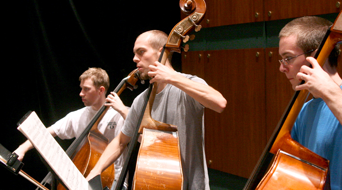 Three students play music on cellos.