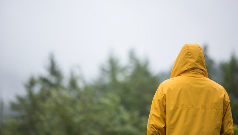 Person with their back turned in yellow rain coat looking into the distance.