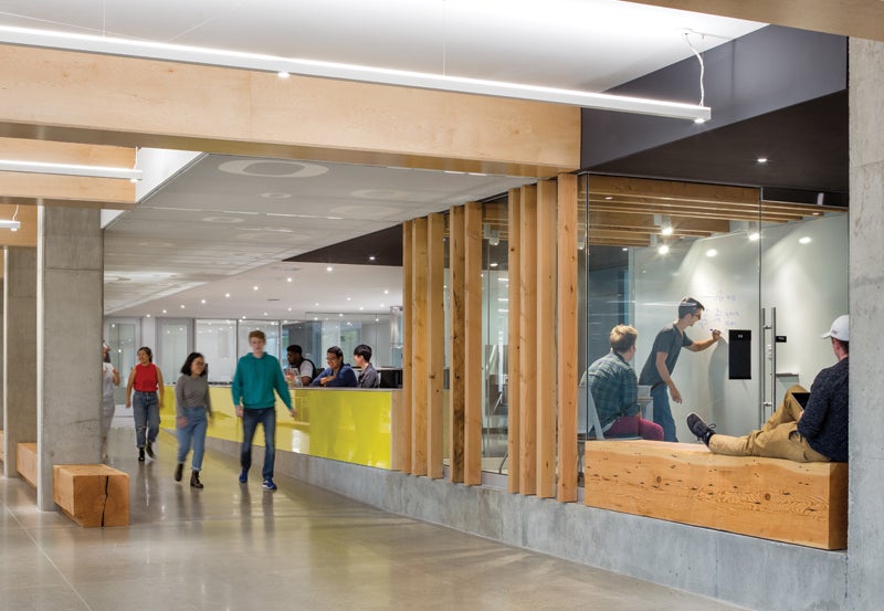 Photo of students walking in building and utilizing study spaces.